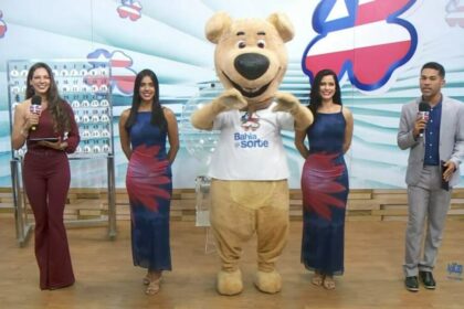 Luck, o mascote de pelúcia do Bahia dá Sorte, ao lado dos apresentadores no centro do palco