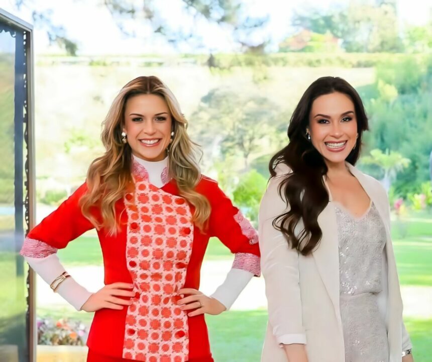 Beca Milano de vermelho e Nadja Haddad de conjunto bege sorridentes no cenário do Bake Off Brasil