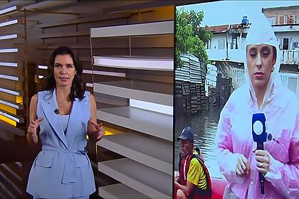 Camila Busnello veste conjunto azul e se aproxima do telão do Fala Brasil para conversar ao vivo com repórter da RECORD que está com capa de chuva e em um bote salva-vidas