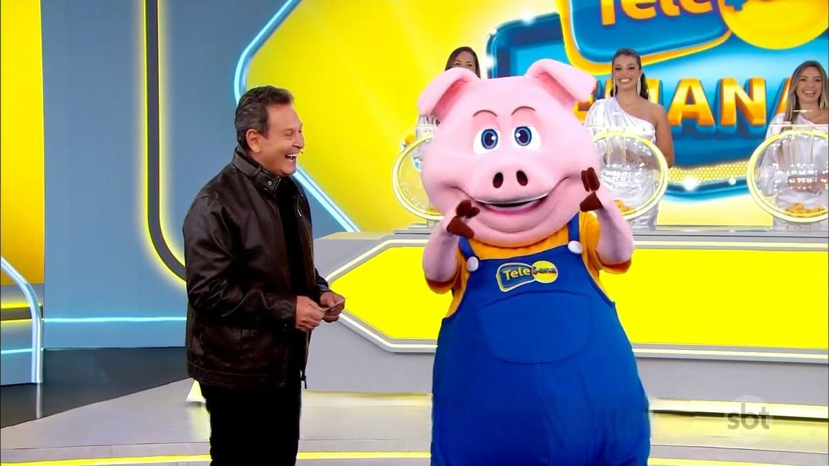 Luiz Ricardo sorrindo ao lado do porquinho no cenário da Tele Sena Semanal