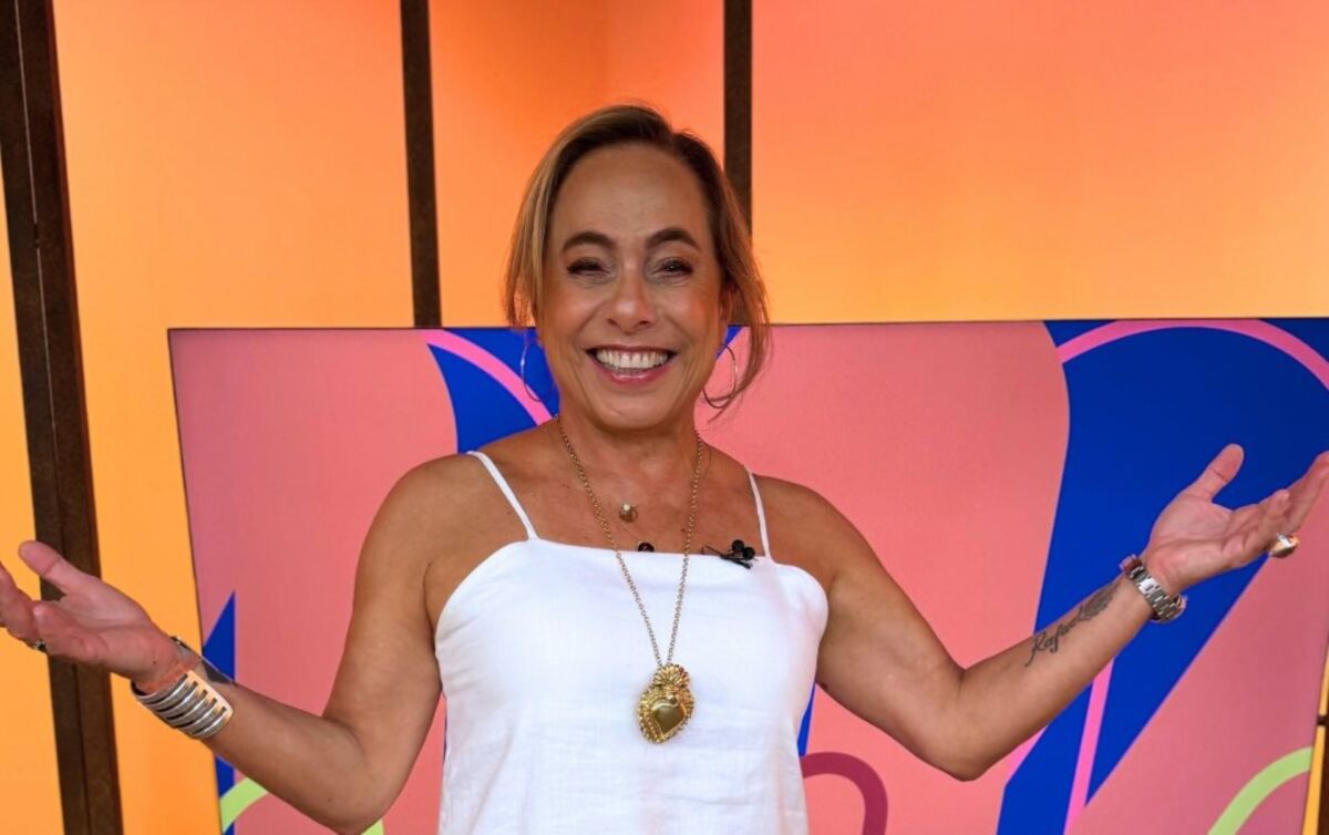 Cissa Guimarães de vestido branco sorrindo no cenário do Sem Censura da TV Brasil