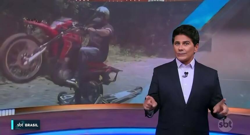 Cesar Filho em frente ao telão do SBT Brasil com uma moto sendo empinada