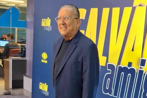 Galvão Bueno em frente a um banner na coletiva do Galvão e Amigos
