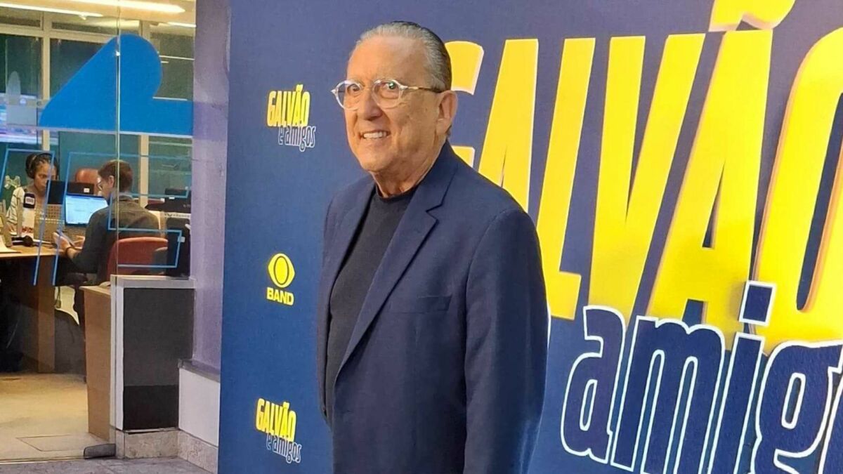 Galvão Bueno em frente a um banner na coletiva do Galvão e Amigos
