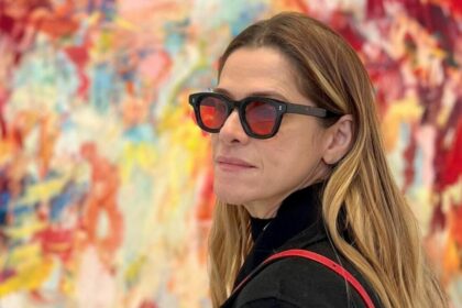 Ingrid Guimarães de óculos escuros em frente a um quadro colorido no fundo