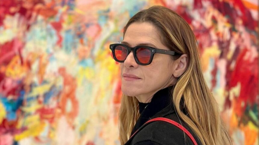 Ingrid Guimarães de óculos escuros em frente a um quadro colorido no fundo