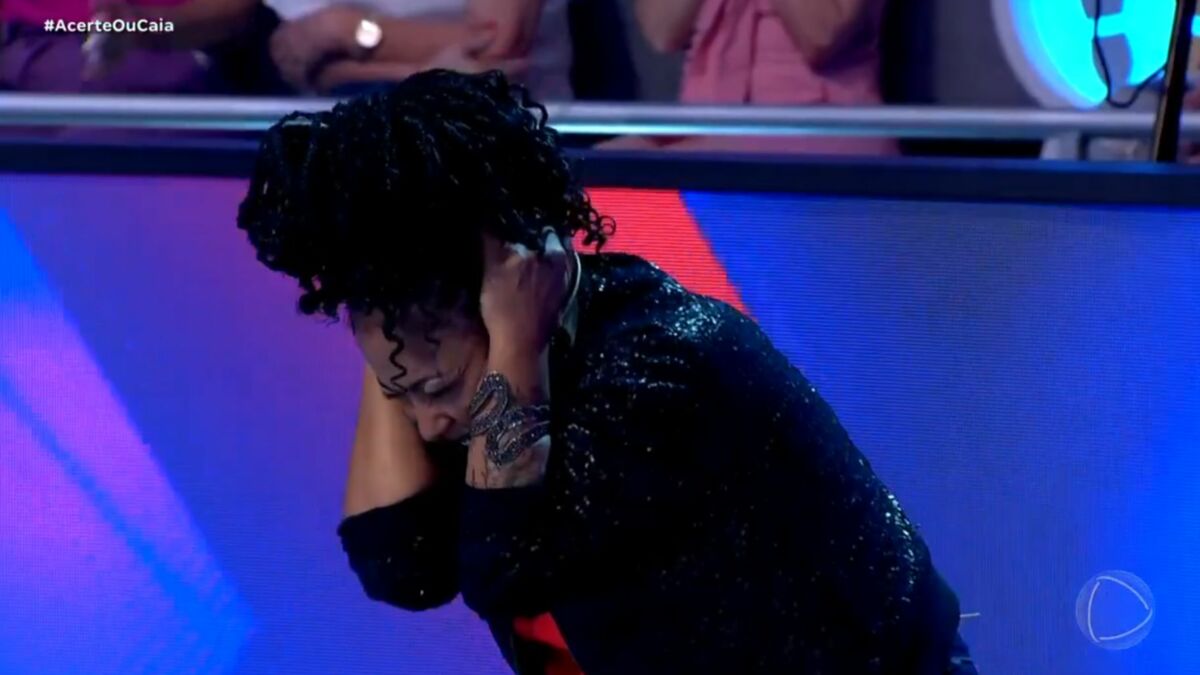 Juliana Oliveira abaixada no Acerte ou Caia, temendo a queda do buraco