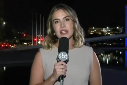 Larissa Alvarenga durante entrada ao vivo no SBT Brasil, segurando o microfone da emissora