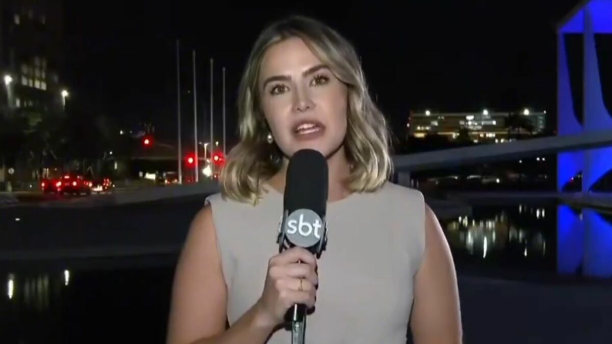 Larissa Alvarenga durante entrada ao vivo no SBT Brasil, segurando o microfone da emissora