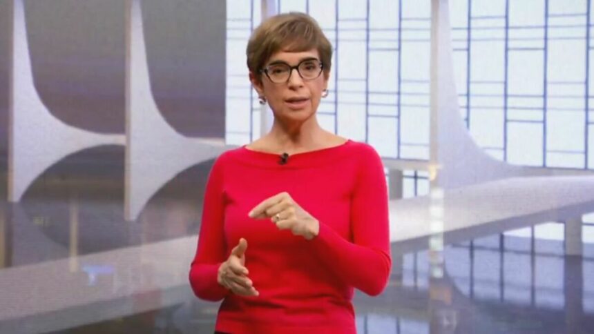 Renata Lo Prete, vestindo suéter vermelho, no cenário do Jornal da Globo