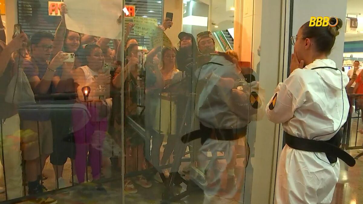 Renata em frente a um espelho, em trecho da dinâmica Vitrine do Seu Fifi