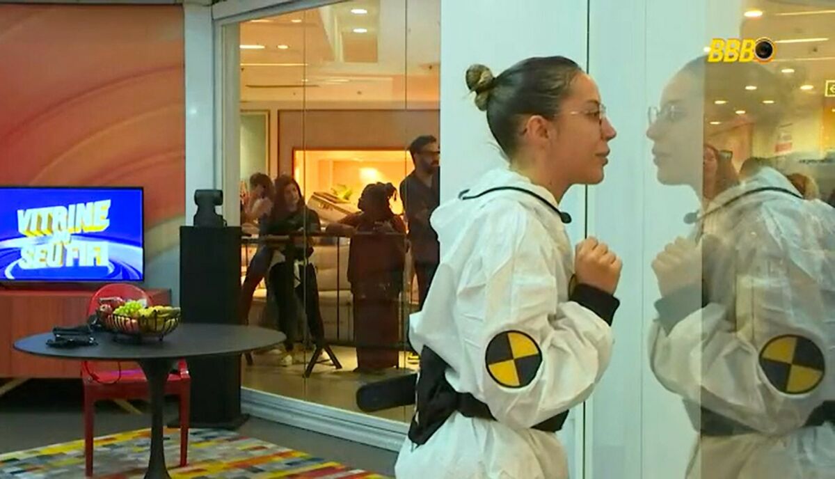 Renata em frente a um espelho, em trecho da dinâmica Vitrine do Seu Fifi