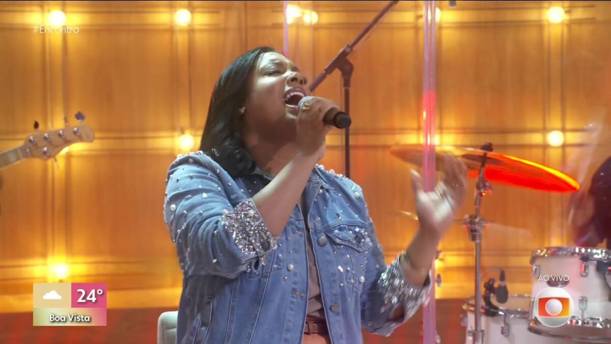 Sued Silva com as mãos levantadas ministrando e cantando no Encontro