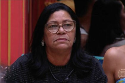 Delma olha sério para o telão onde Tadeu aparece na sala do BBB 25