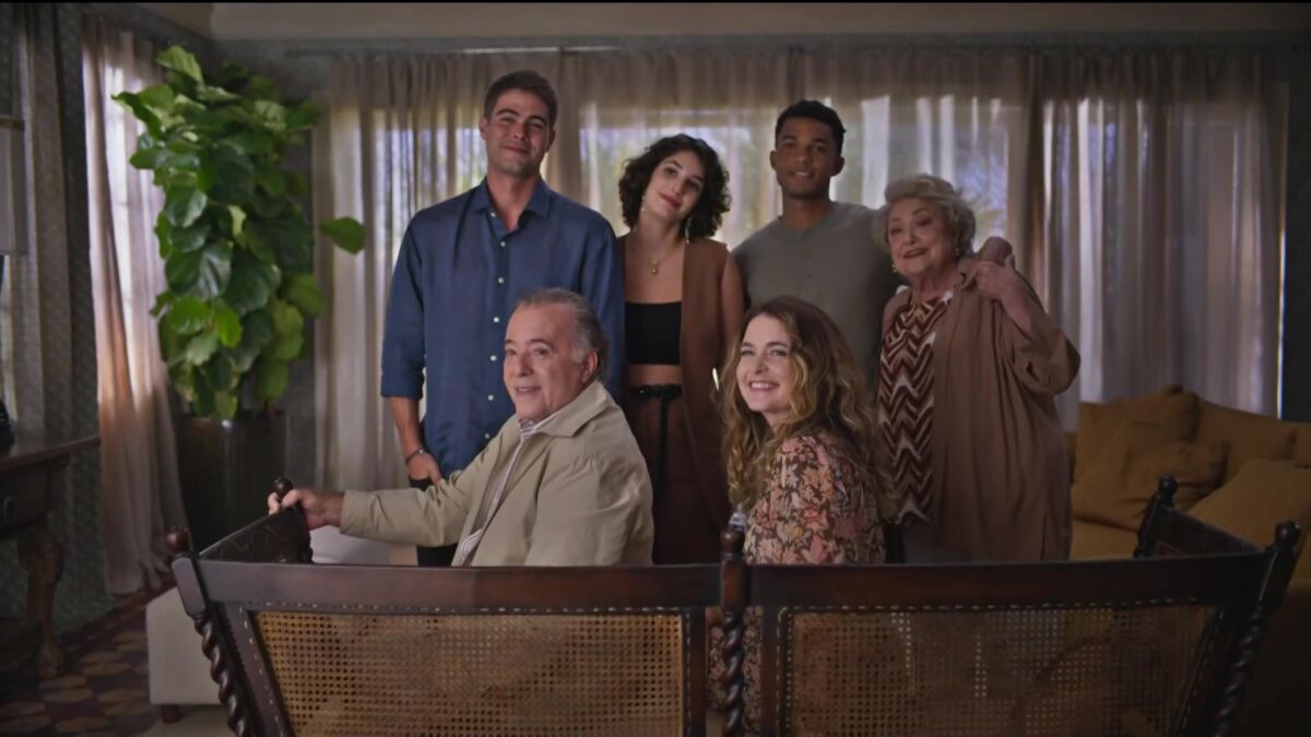 Tony Ramos, Cláudia Abreu e outros atores em uma sala, cenário de Dona de Mim, olhando para a protagonista da novela da sete Dona de Mim. todos estão sorrindo