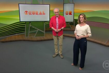 Nélson Araújo veste camisa rosa e Helen Martins uma blusa cor nude com calça azul no cenário do Globo Rural