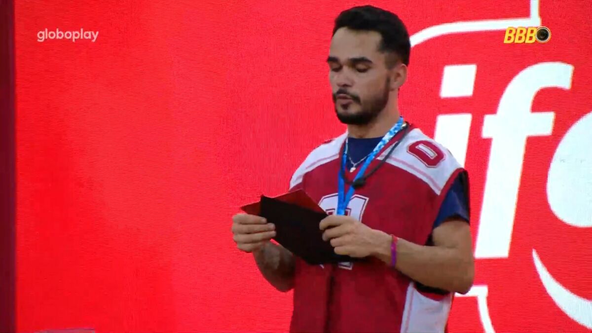 João Pedro ler o castigo do monstro com o colar da imunidade no pescoço no gramado do BBB 25
