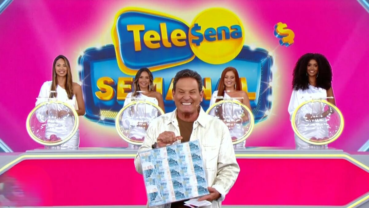Luiz Ricardo segura maleta com cédulas de 100 reais no cenário rosa da Tele Sena Semanal edição 44