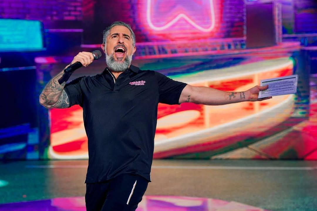 Marcos Mion de braços abertos no palco do Caldeirão