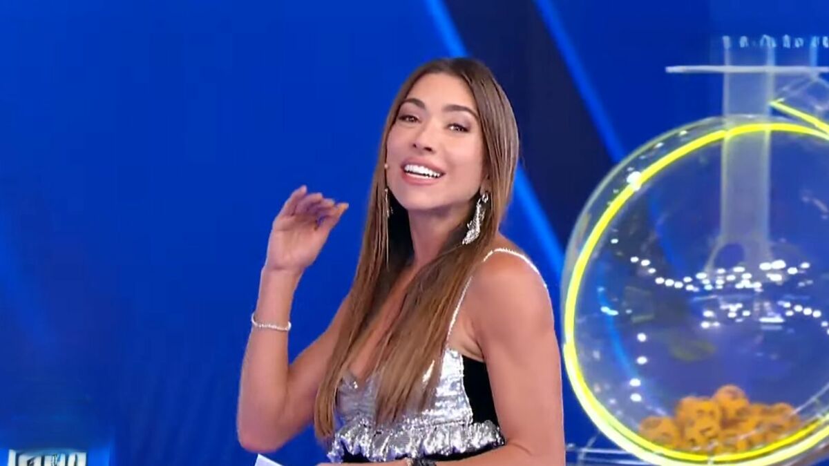 Patricia Abravanel, de roupa branco com preto, no cenário do sorteio da Tele Sena de Páscoa 2025