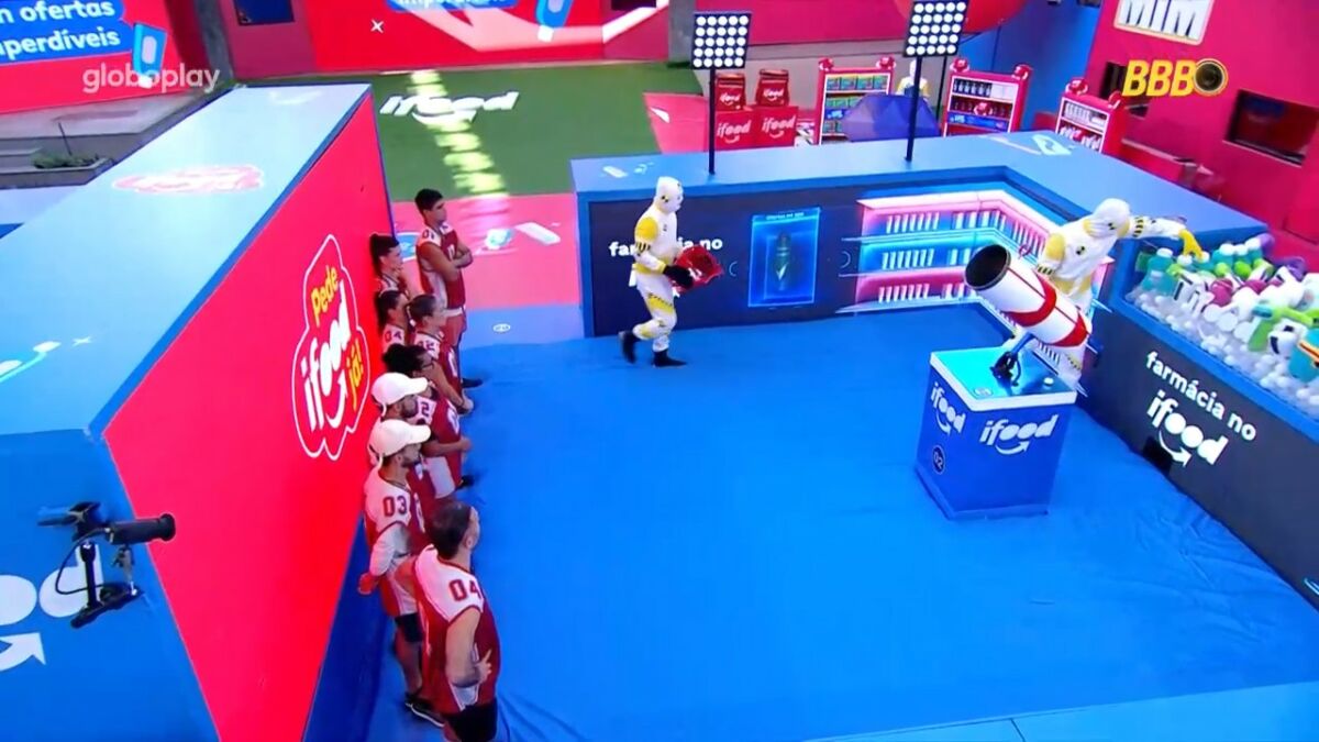 Brothers em pé, na frente de uma parede azul, no local da Prova do Anjo do BBB 25