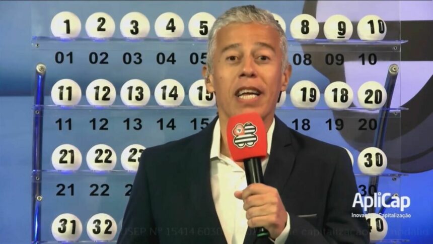 Apresentador segura o microfone do São Paulo dá Sorte, em frente ao painel com as bolas do sorteio