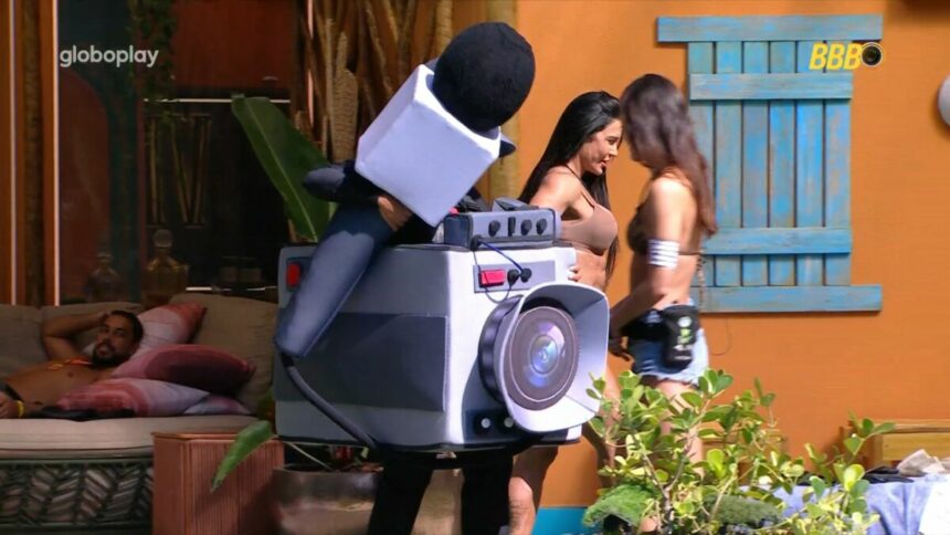 Thamiris vestida com Castigo do Montro que é uma câmera gigante de pelúcia na beira da piscina do BBB 25