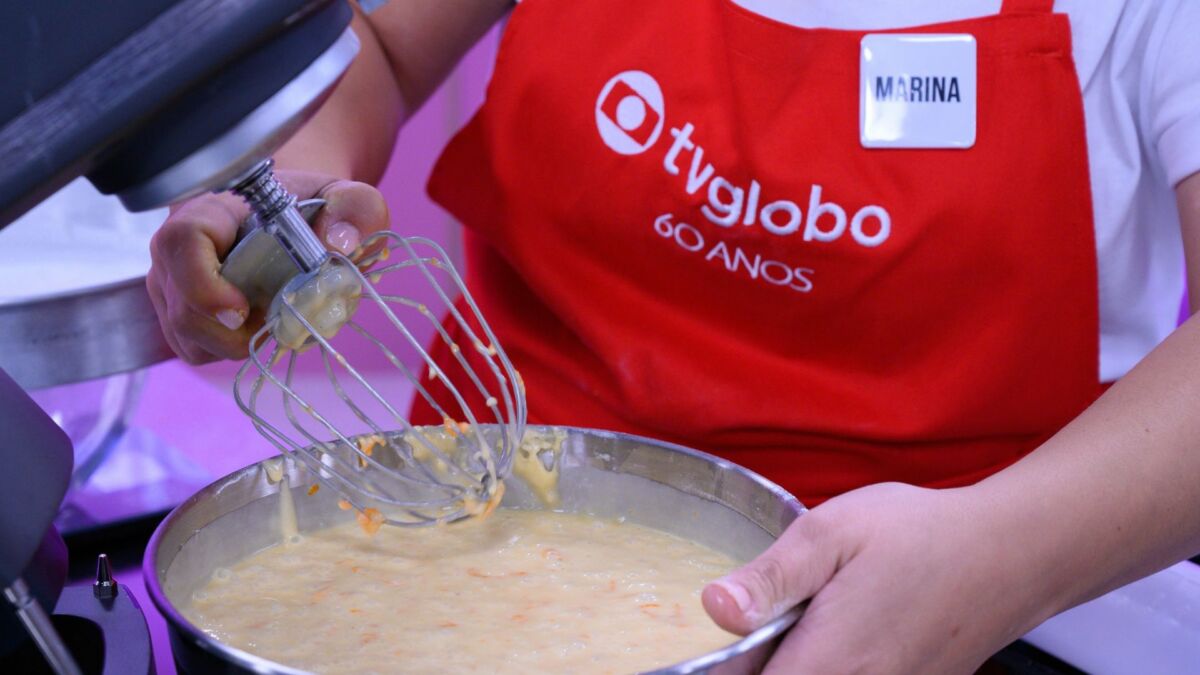 Confeiteira, com avental vermelho, em trecho do reality no Mais Você