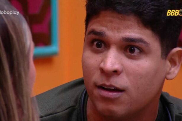 Guilherme com a boca aberta e os olhos arregalados olhando para Renata no sofá da sala do BBB 25