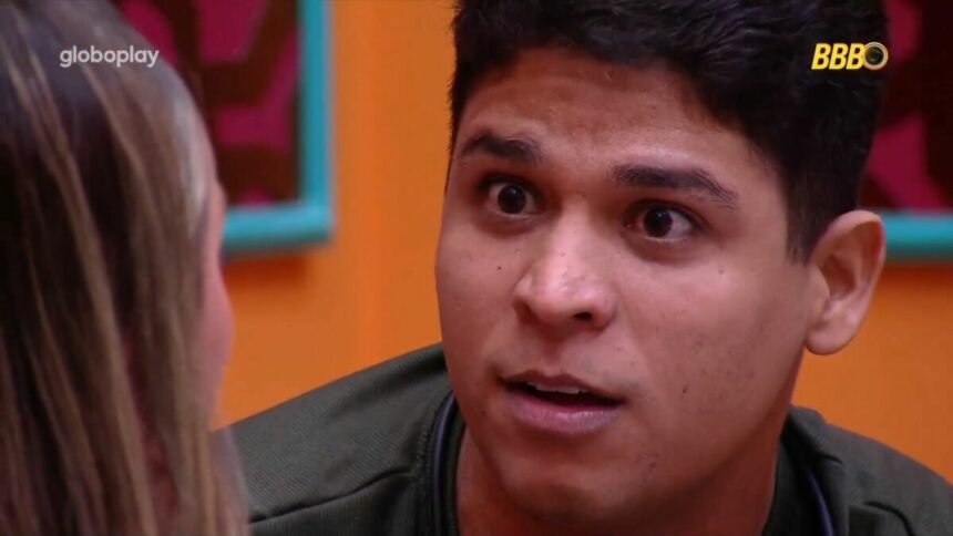 Guilherme com a boca aberta e os olhos arregalados olhando para Renata no sofá da sala do BBB 25