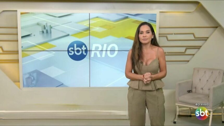 Isabele Benito com semblante sério em frente ao logo do SBT Rio