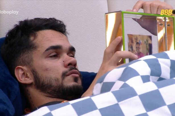 João Pedro deitado na cama e segurando a foto da família no BBB 25