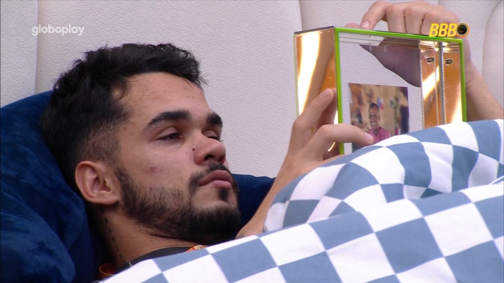 João Pedro deitado na cama e segurando a foto da família no BBB 25