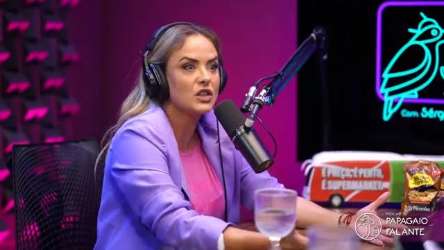 Juliana Silveira de terno lilás e blusa rosa em frente a um microfone de podcast onde revelou denúncia de assédio em novela da RECORD