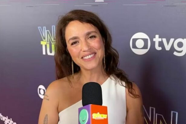 Manuela Dias em entrevista ao Gshow em frente a um banner de Vale Tudo