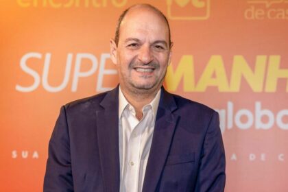 Mariano Boni em foto posada em frente a um banner das 'Super manhãs' da Globo