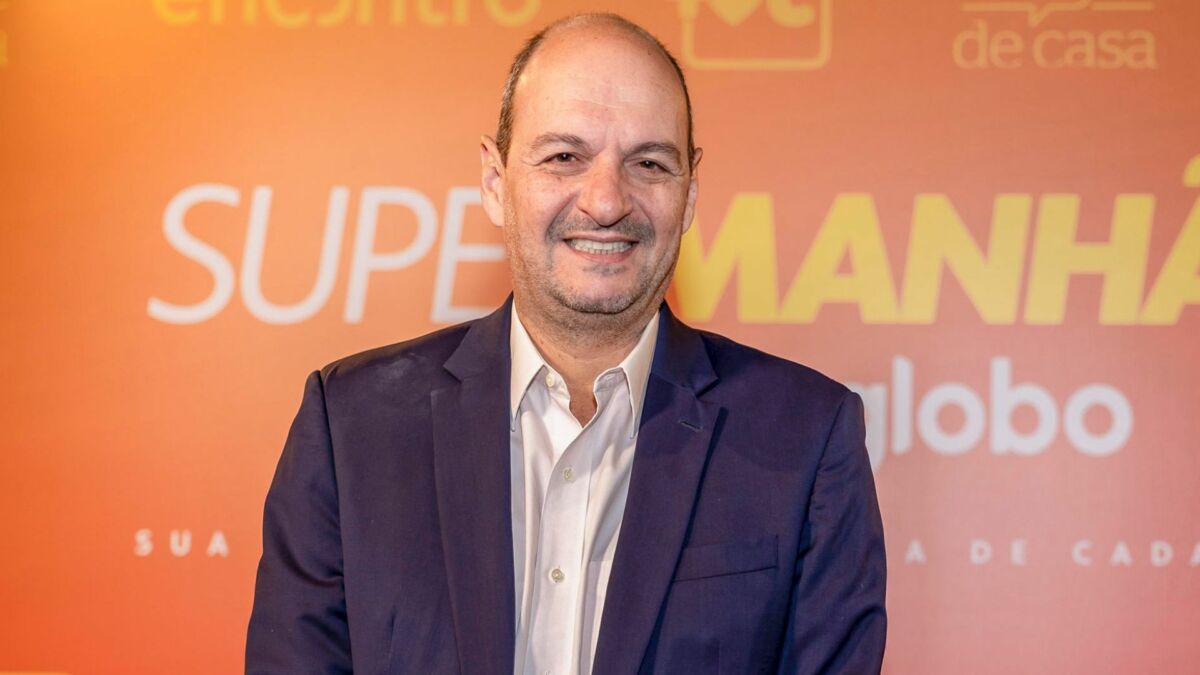 Mariano Boni em foto posada em frente a um banner das 'Super manhãs' da Globo