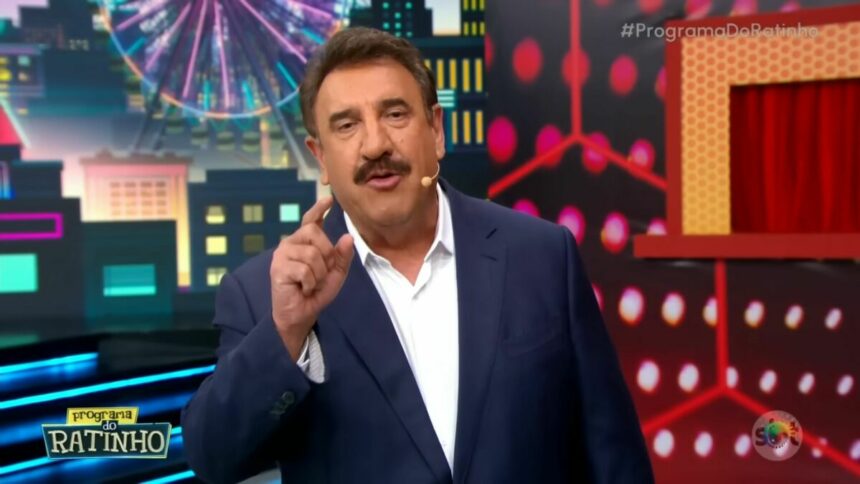 Ratinho de terno e camisa branca levanta o dedo enquanto apresenta o Programa do Ratinho no SBT