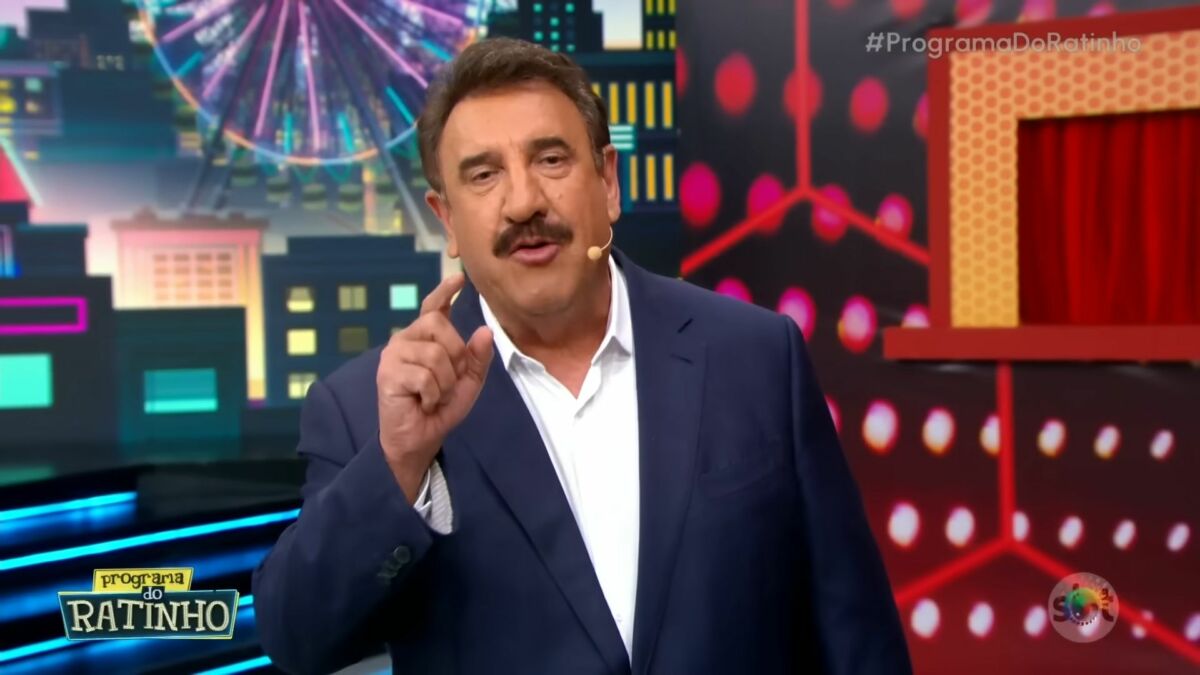 Ratinho de terno e camisa branca levanta o dedo enquanto apresenta o Programa do Ratinho no SBT