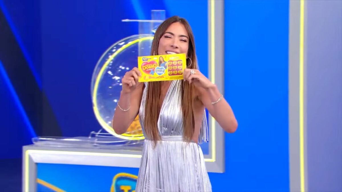 Patricia Abravanel sorrindo e segurando o bilhete do segundo sorteio da Tele Sena de Mães 2025