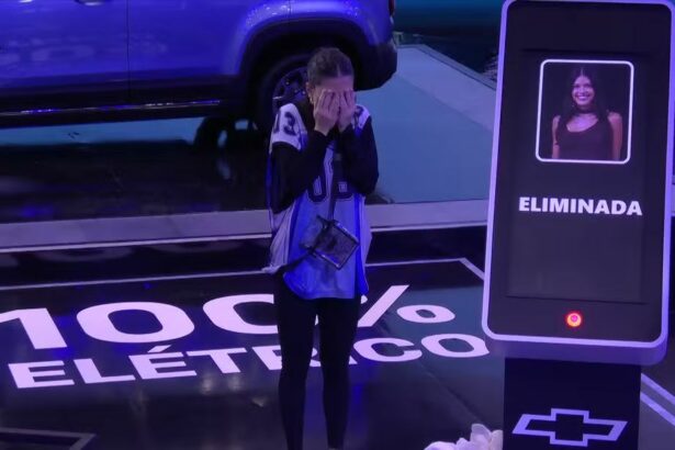 Vitória Strada chora ao ser eliminada da Prova do Finalista ao lado do carro da chevrolet. Ela coloca as mãos no rosto