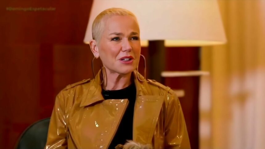 Xuxa de jaqueta marrom brilhosa, olhando para Carolina Ferraz na entrevista à RECORD