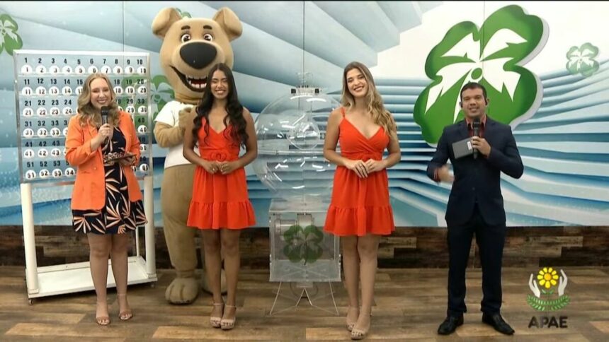 Apresentadores do Alagoas dá Sorte com o mascote e as assistentes de palco, que vestem vestido laranja no sorteio deste domingo 20 de abril