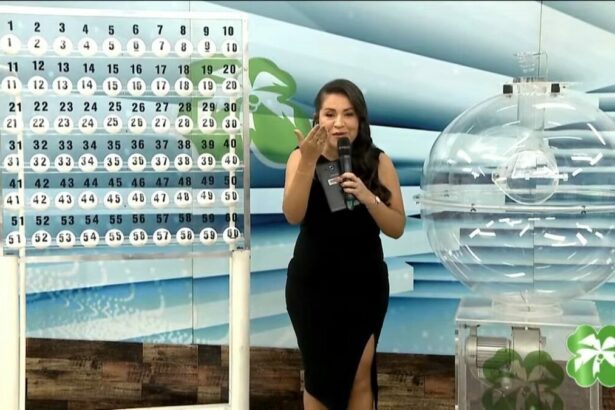 Apresentadora do Alagoas dá Sorte de vestido preto apresentando o painel com as bolas do sorteio do dia 27 de abril