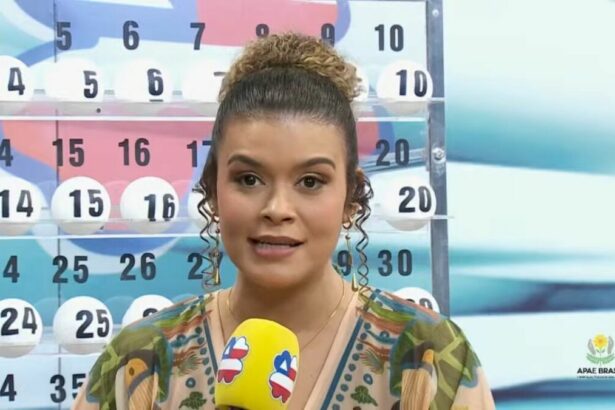 Apresentadora em pé segurando o microfone do Bahia dá Sorte em frente ao expositor com as bolas do sorteio no sorteio deste domingo 20 de abril