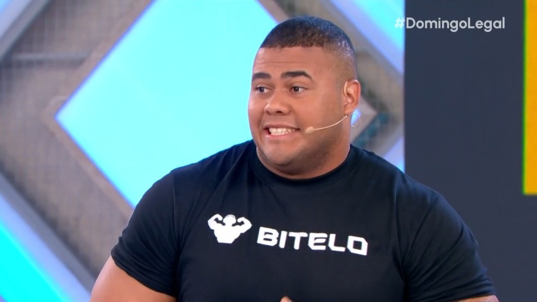 Bitelo de camisa preta e com semblante assustado no palco do Domingo Legal
