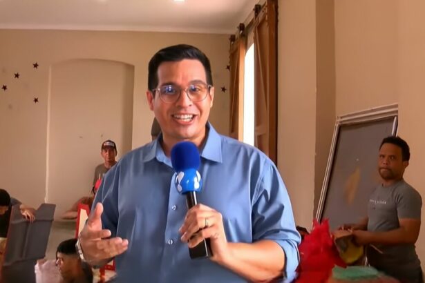 Bruno Araújo segura o microfone da RedeTV! e sorrir
