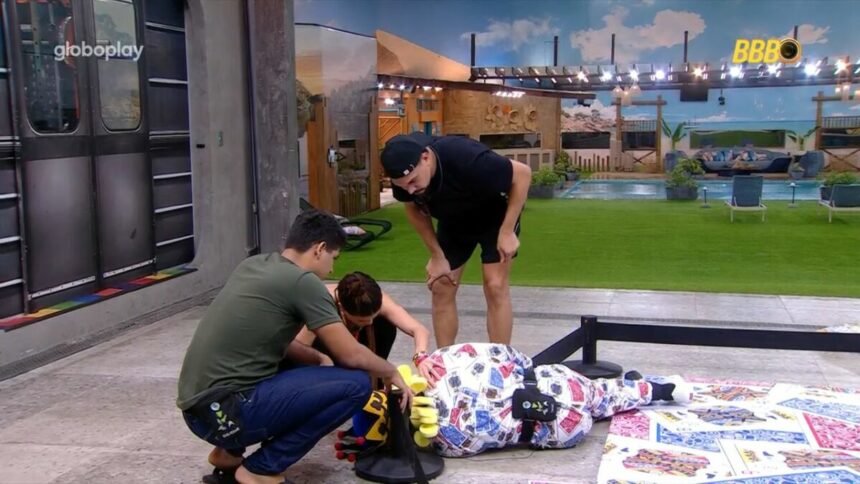 Diego Hypolito, vestido de Rei, caído no chão do Castigo do Monstro do BBB 25. Vinicius, Guilherme e Vitória Strada ao lado tentando ajudar