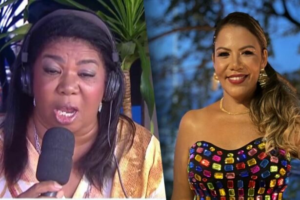Elisangela com o microfone e fone de ouvido na porta da RECORD Bahia. Ela está com a boca aberta concedendo entrevista. Mani Rego veste um cropped colorido de pedras brilhantes. Ela está no entardecer e sorrindo.