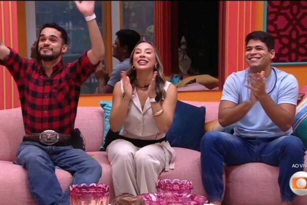 João Pedro batendo palma ao lado de Renata que também bate palma e Guilherme que sorrir, sentados no sofá do BBB 25 ao descobrir que estão na final